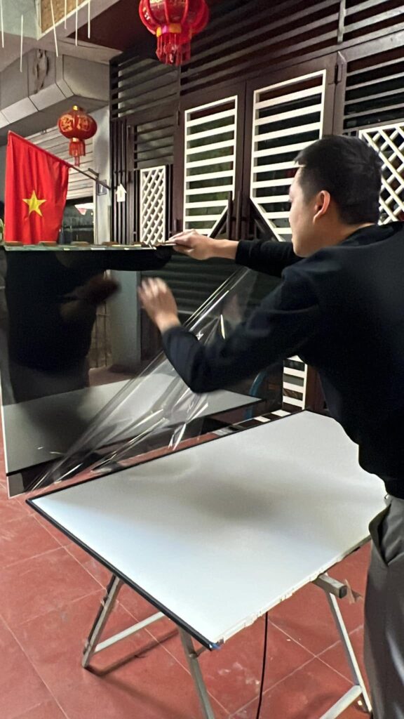 Kỹ thuật viên bóc màng bảo vệ tấm màn hình tivi mới khi thay màn hình